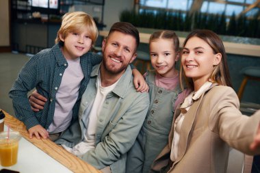 Hollandalıların güzel çocukları ve kocasının yanında oturan ve ellerinde akıllı telefonuyla yemek salonunda selfie çekerken çektikleri gülümseme açısı.