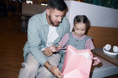 Hollanda açılı bir fotoğraf. Babası, paketleri açarken kese kağıdına bakan kızını kucaklarken çekilmiş. Fotoğraf makinesi flaşı ile göstermişler.