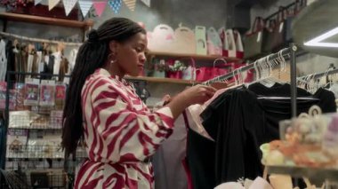 Moda mağazasında moda kıyafetlerini kontrol eden siyah kadın müşterinin düşük açılı görüntüsü