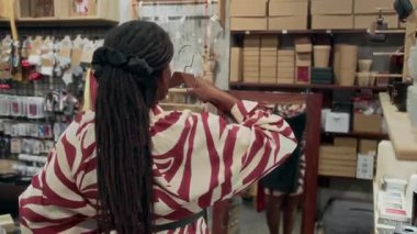 Aynanın karşısında iki elbise tutan Afro-Amerikalı kadının arkası. Moda mağazasında uygun mu diye görmek için.