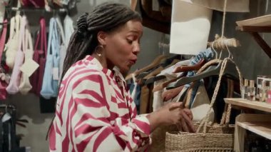 Orta boy, şık giyinmiş, alışveriş merkezinden çanta seçen Afrikalı Amerikalı bir kadın.