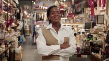 İş yerinde kameraya gülümseyen zarif bluzlu Afrikalı Amerikalı kadın mağaza çalışanının orta boy portresi.