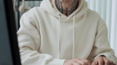 Ofisteki bilgisayarda çalışırken, kafkasyalı, dövmeli, endişeli bir çalışanın görüntüsünü öne eğ.