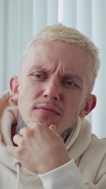 Kapalı alanda çalışırken görev çözümünü düşünen dövmeli beyaz adamın dikey çekimi.