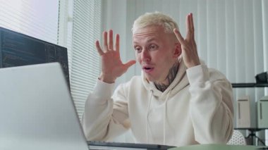 Ofisteki senaryolarla uğraşırken dizüstü bilgisayarın önünde oturan beyaz dövmeli mutlu bir adamın orta boy fotoğrafı.