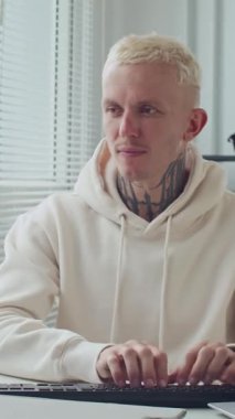 Ofisteki bilgisayarda genç erkek geliştiricinin dikey görüntüsü.