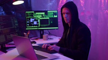 Beyaz erkek hacker programının karanlık odada siber saldırıya hazırlanırken orta boy görüntüsü.