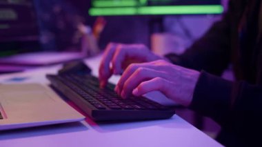 Neon odada programlama yaparken bilgisayarın klavyesinde yazan tanınmayan erkek hacker 'ın ellerini yakın plan çek