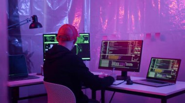 Masadaki dijital ekipman üzerine kırmızı başlık programlı genç Kafkas siber suçlarının neon görüntüsü.