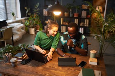 Çevrimiçi projeyi bilgisayar üzerinde tartışan, yeşil santrallerle birlikte ekonomi ofisinde çalışan meslektaşların yüksek açılı görüntüsü