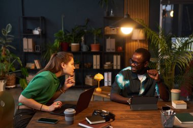 Meslektaşlar bilgisayarlarla masaya oturur ve ekonomi ofisinde online işler yaparlar.