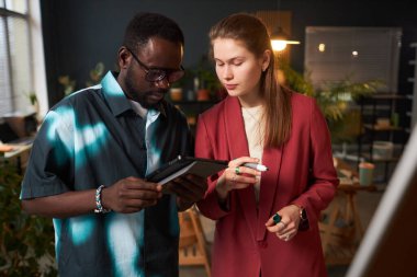 Ofisteki takım çalışması sırasında dijital tablet kullanan ve yeni çevrimiçi proje üzerinde çalışan meslektaşlar