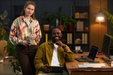 Çevre ofisindeki güvenlik kodlarıyla çalışırken kameraya gülümseyen programcıların portresi