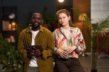 Ofiste birlikte çalışan genç iş arkadaşlarının portresi yeşil bitkilerle