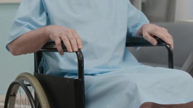 Hastane odasında tekerlekli sandalye kullanan yaşlı ve kimliği belirsiz bir hastanın görüntüsü.