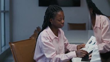 Formalite içinde iki etnik menajerin masadaki iş çizelgelerini geniş ofis alanındaki dizüstü bilgisayarla tartışırken orta boy bir fotoğrafı.