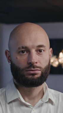 Ofiste kameraya bakan beyaz sakallı bir iş adamının dikey portresi.