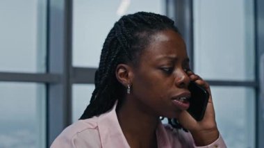 Afrika kökenli Amerikalı iş kadınının iş yerindeki cep telefonundan aradığı orta boy yakın çekim.