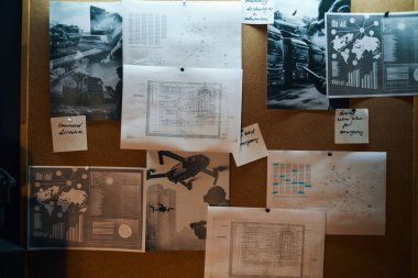 Mantar panoya iğnelenmiş diyagram kaplı kağıtlar veri analizi ve araştırmalarla ilgili çeşitli grafikler, grafikler ve haritalar içeriyor. Bazı çarşaflar düzenli olarak düzenlenirken, diğerleri gelişigüzel yerleştirilmiştir.