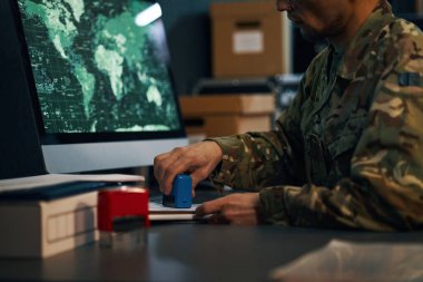 Harita verilerini gösteren bilgisayar monitörleriyle çalışan askeri üniformalı biri. Düzenli bir ortamda teknik operasyonlara girişmek