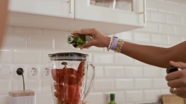 Ev mutfağında blender pişirirken zeytin yağı ekleyen tanınmayan insanların el resimleri.