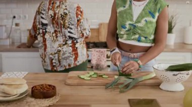 Genç kızın evde yemek pişirirken annesiyle konuştuğu görüntüyü yakınlaştır.