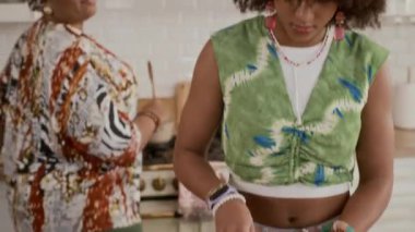 Çok ırklı kız ve annenin hafta sonları evde birlikte yemek pişirirken çekilmiş bir fotoğrafı.