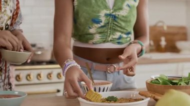 Tanımlanamayan anne ve kızının, ev yemeği için çeşitli yiyeceklerle servis masası çekimleri.