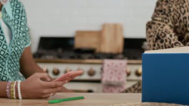 Tanımlanamayan bir annenin, mutfakta ödev yaparken kızına akıllı telefon kullanmayı bırakmasını söylemesi.