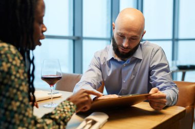 Restoranda otururken menüyü inceleyen çok ırklı bir çift.