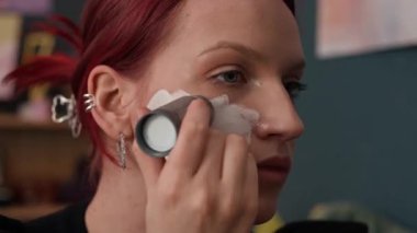 Makyaj yaparken beyaz temeli kullanan beyaz saçlı, beyaz saçlı genç kadının yakın plan görüntüsü.