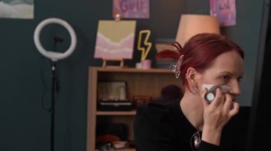 Kızıl saçlı, aynanın önüne makyaj yapan ve kameraya bakan Kafkas genli Z kızının göğüs yukarı portresi.