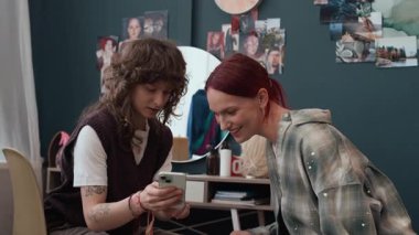 İnternette makyaj fikirleri ararken akıllı telefon ekranına bakıp onları tartışan iki neşeli kız arkadaş.