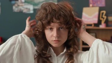 Kontak lensli kıvırcık saçlı Z-Kızı, piercing yaptırmış burun ve göğüs dövmesi, kameraya poz veriyor ve evde canlı yayına hazırlanıyor.