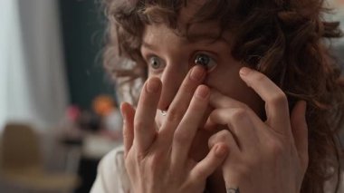 Kafkasyalı kıvırcık saçlı, septum piercingli, siyah lens takan ve kameraya bakan kız.