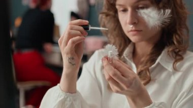 Beyaz dekoratif tüye kozmetik yapıştırıcı sürerken evde makyaj yaparken yüzüne yapıştırmadan önce beyaz saçlı, beyaz bir kadının odak noktası.