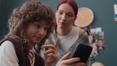 İnternette akıllı telefon kullanarak makyaj stili seçerken etkin iletişim kuran iki kızın görüntüsünü büyüt