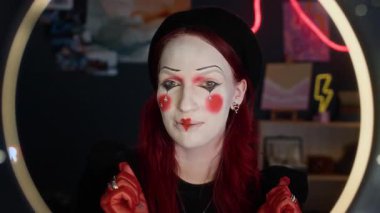 Yüzük lambası kullanarak sosyal medya için canlı yayın yaparken kameraya konuşan, makyaj, şapka, eldiven ve aksesuar takan neşeli kızıl saçlı kızın POV 'u.