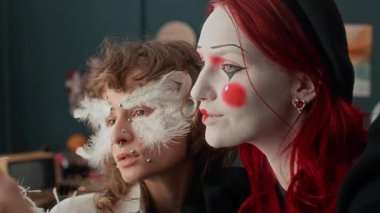 Yakın çekimde, melek gibi giyinen ve makyaj yapan iki Z kız arkadaşının evde akıllı telefonuyla selfie çekerken.