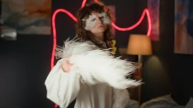 Kafkas kıvırcık saçlı, beyaz açık renk elbiseli, tüylü makyajlı, odasında kameraya bakan kızın portresini yakınlaştır.