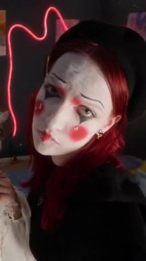 Ev partisi sırasında kameraya poz veren yaratıcı makyaj ve kostüm giymiş iki beyaz kadının dikey görüntüsü.