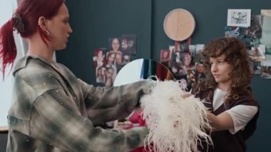 Evde sosyal medya videoları çekmeden önce beyaz boa ve pembe moda aksesuarları takan iki kız arkadaş.