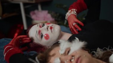 Kostümlü ve makyajlı iki Z jenerasyonunun odak portresini büyüt. Evde yatakta uzanan kameraya dramatik şekilde bak.