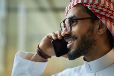 Gözlüklü, telefonla konuşan, uzayı kopyalayan kendinden emin genç Orta Doğulu erkek CEO 'nun yakın çekimi.