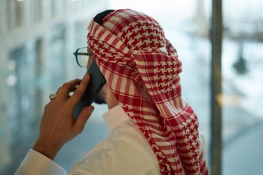 Orta Doğulu tanınmayan işadamının telefonla konuşurken pencereden dışarı baktığı arka plan görüntüsü