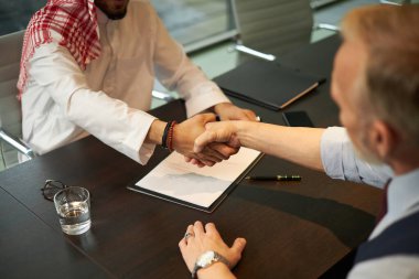 Etnik çeşitliliğe sahip iki işadamının anlaşma imzaladıktan sonra el sıkışması