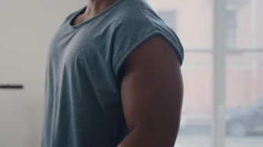 Güçlü Afrikalı Amerikalı adamın ağırlık kaldırma egzersizi sırasında halterle tek kol bisepsi kıvrımlarını yukarı kaldır.