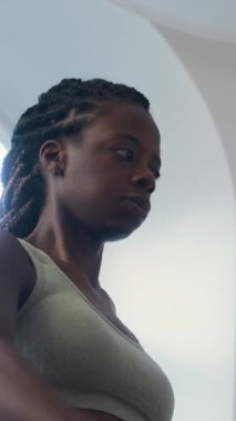 Afrika kökenli Amerikalı bir kadının spor salonunda ağırlık çalışırken halterin önünde yükseldiği dik açılı bir çekim.