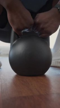 Ağırlık kaldırma egzersizi sırasında spor salonundan kettlebell alan tanınmayan siyahi bir adamın dikey yakın çekimi.