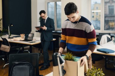 Ofiste yeni bir işe giren bir işçi, eşyalarını işyerine yerleştiriyor.